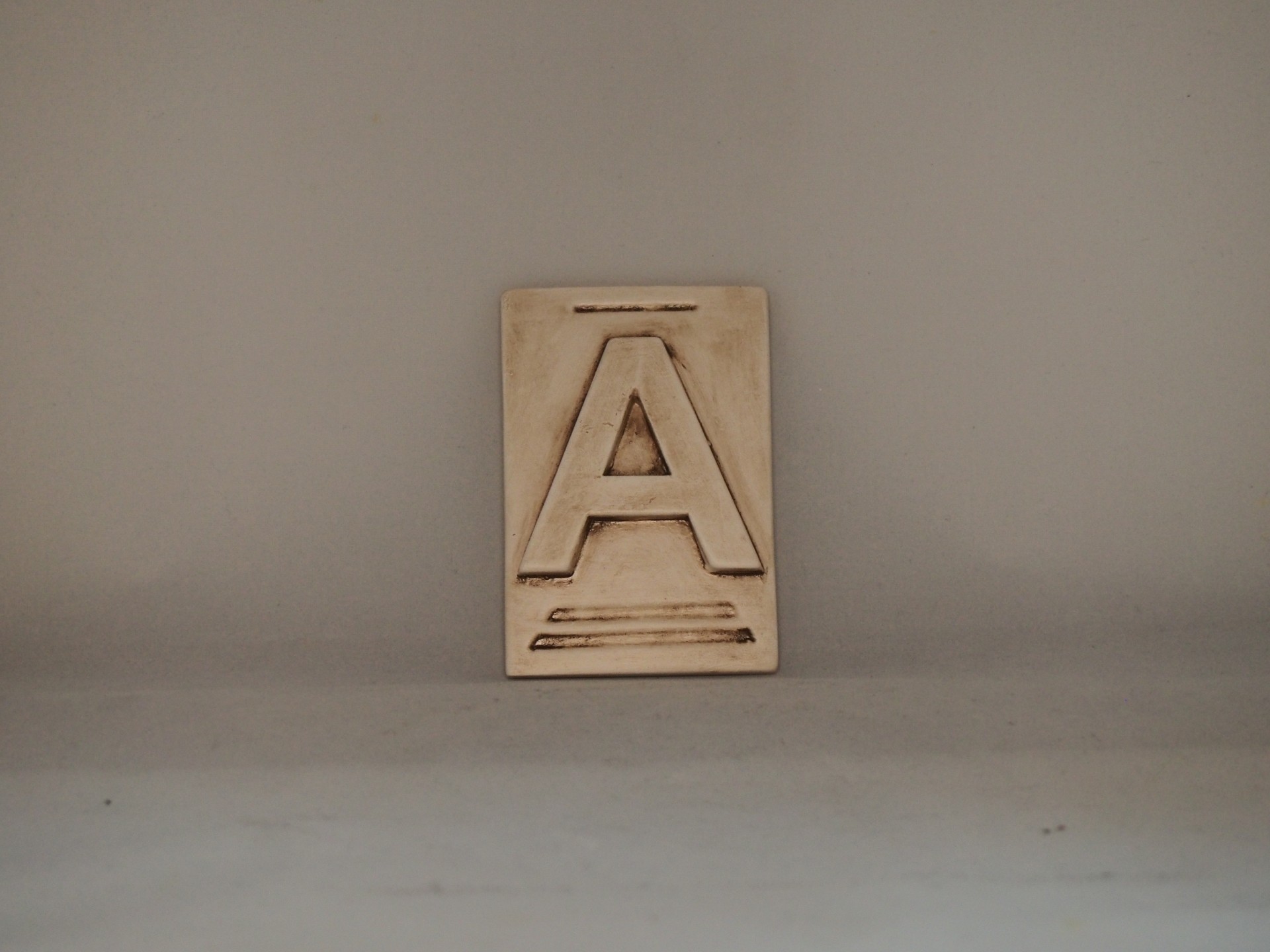 Placa decorativa com a letra A em relevo
