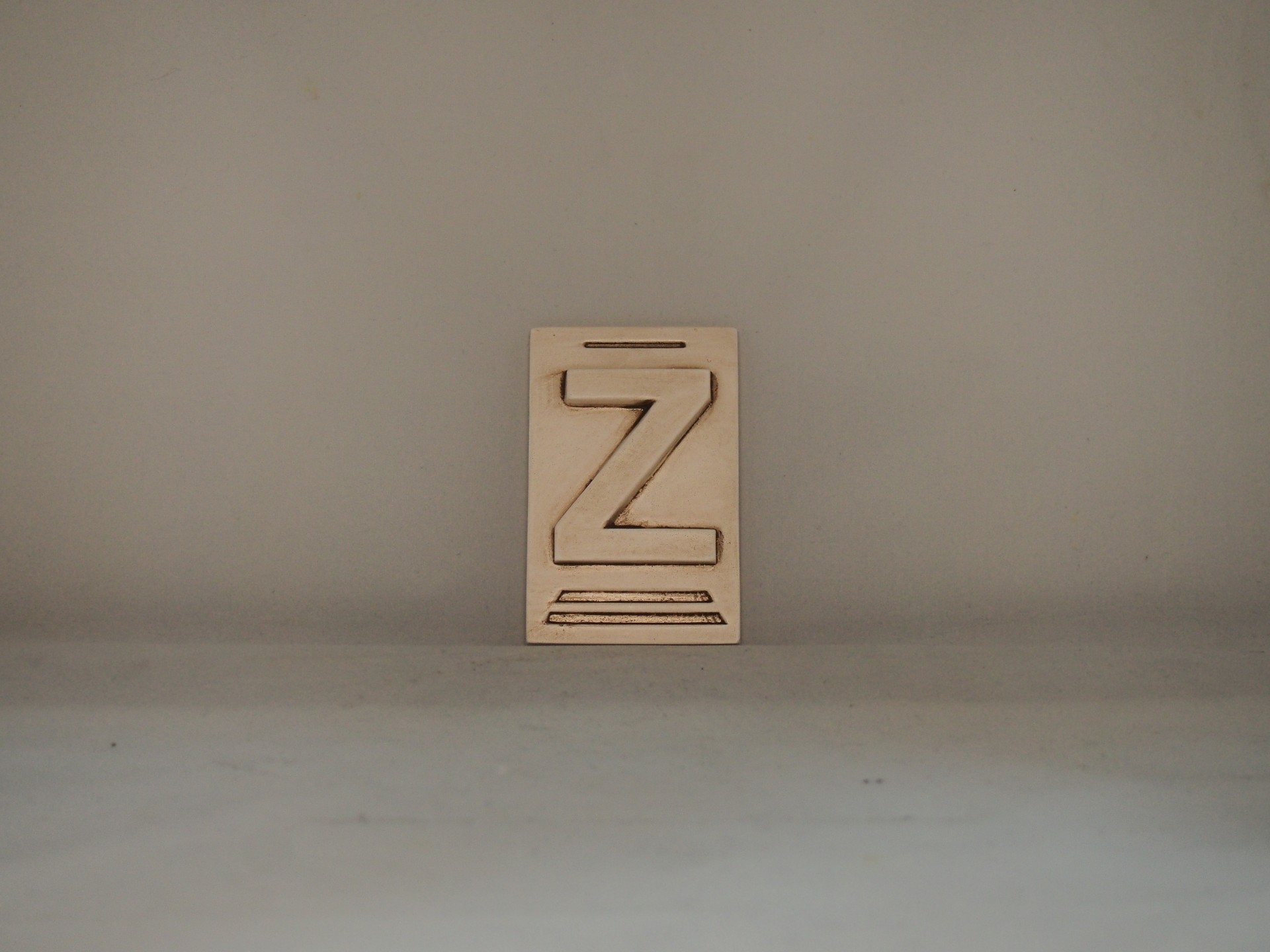 Placa de madeira clara com letra 'Z' recortada em relevo