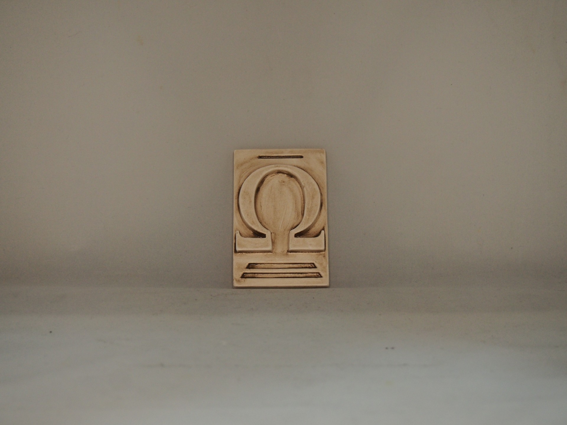 Placa de madeira com relevo do símbolo Ômega