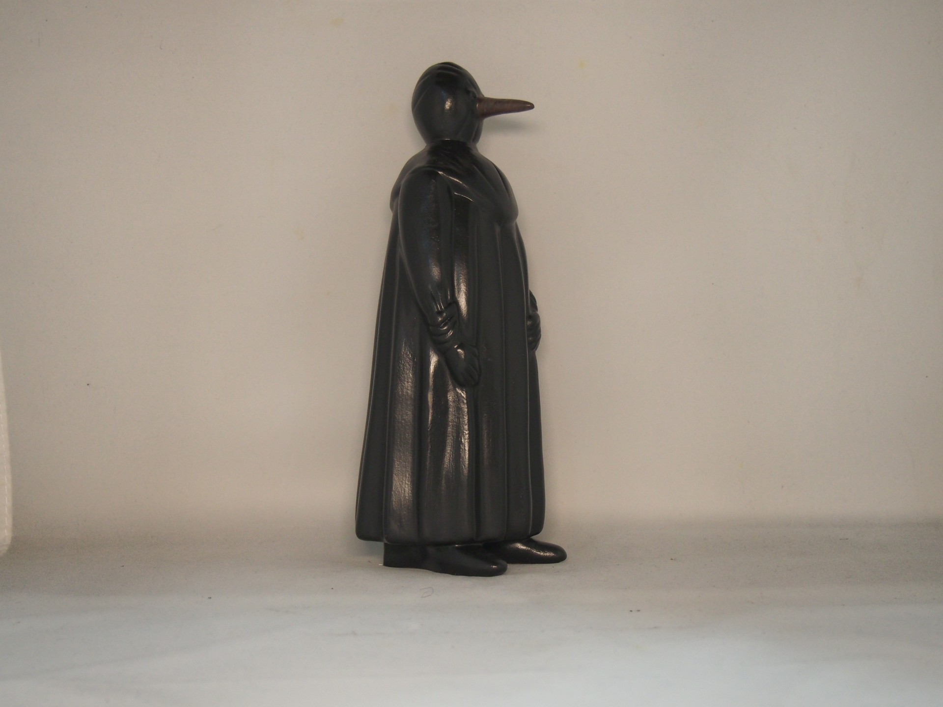 Figura decorativa preta em forma de animal com bico em fundo neutro