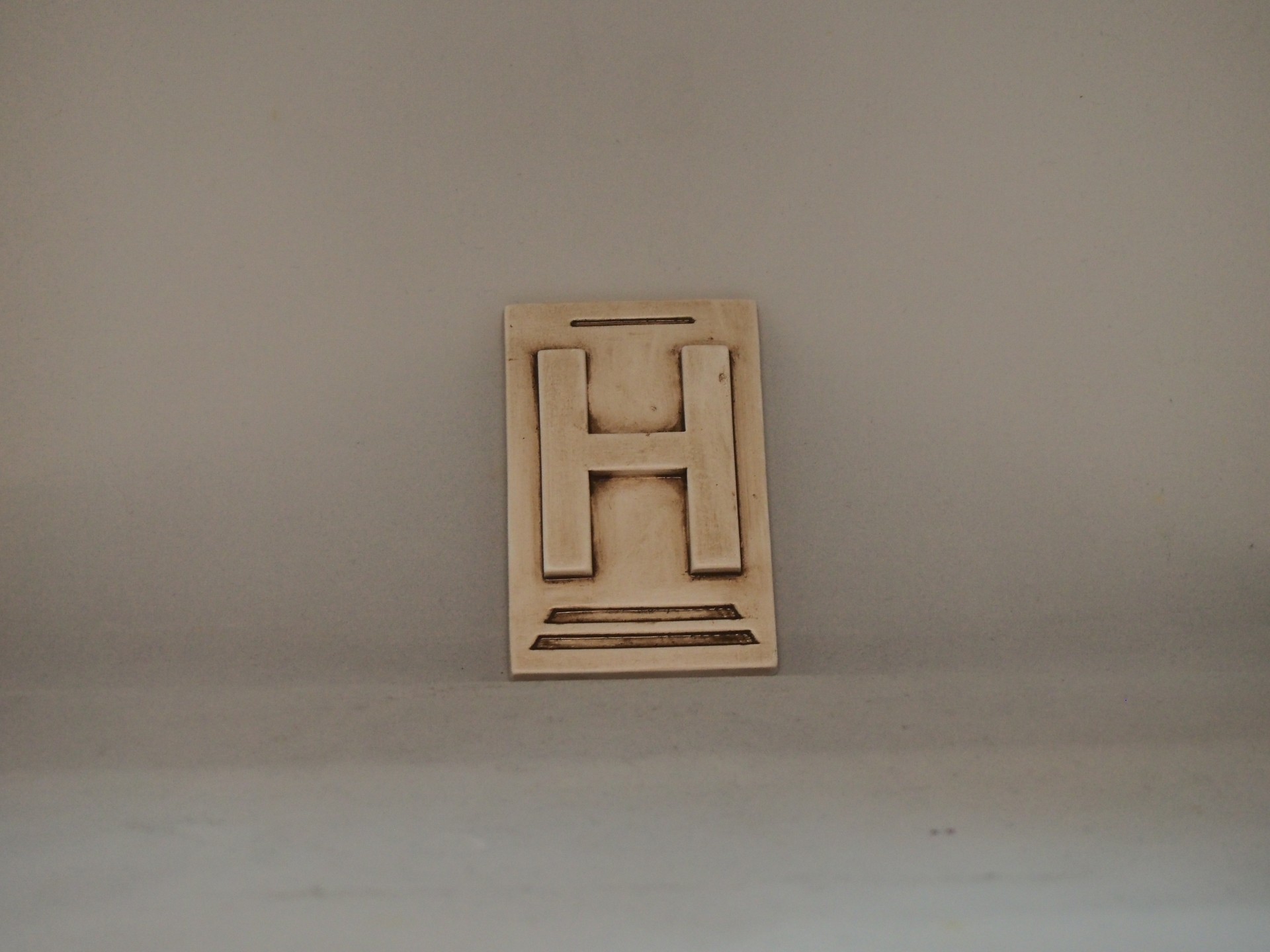 Placa de madeira com a letra H em relevo