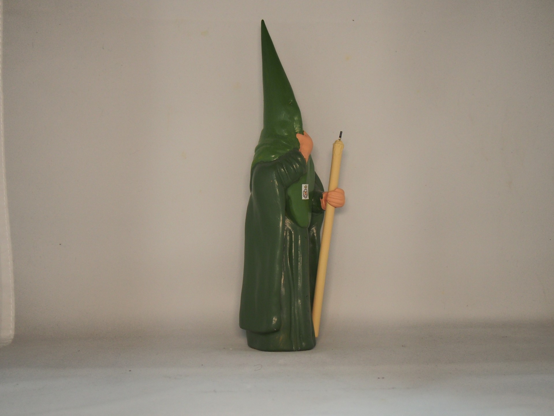 Estatueta de gnome verde segurando bastão amarelo