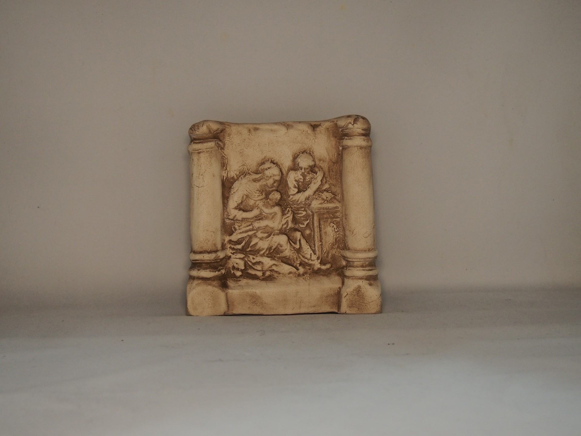 Relevo decorativo quadrado bege com figuras humanas entre colunas