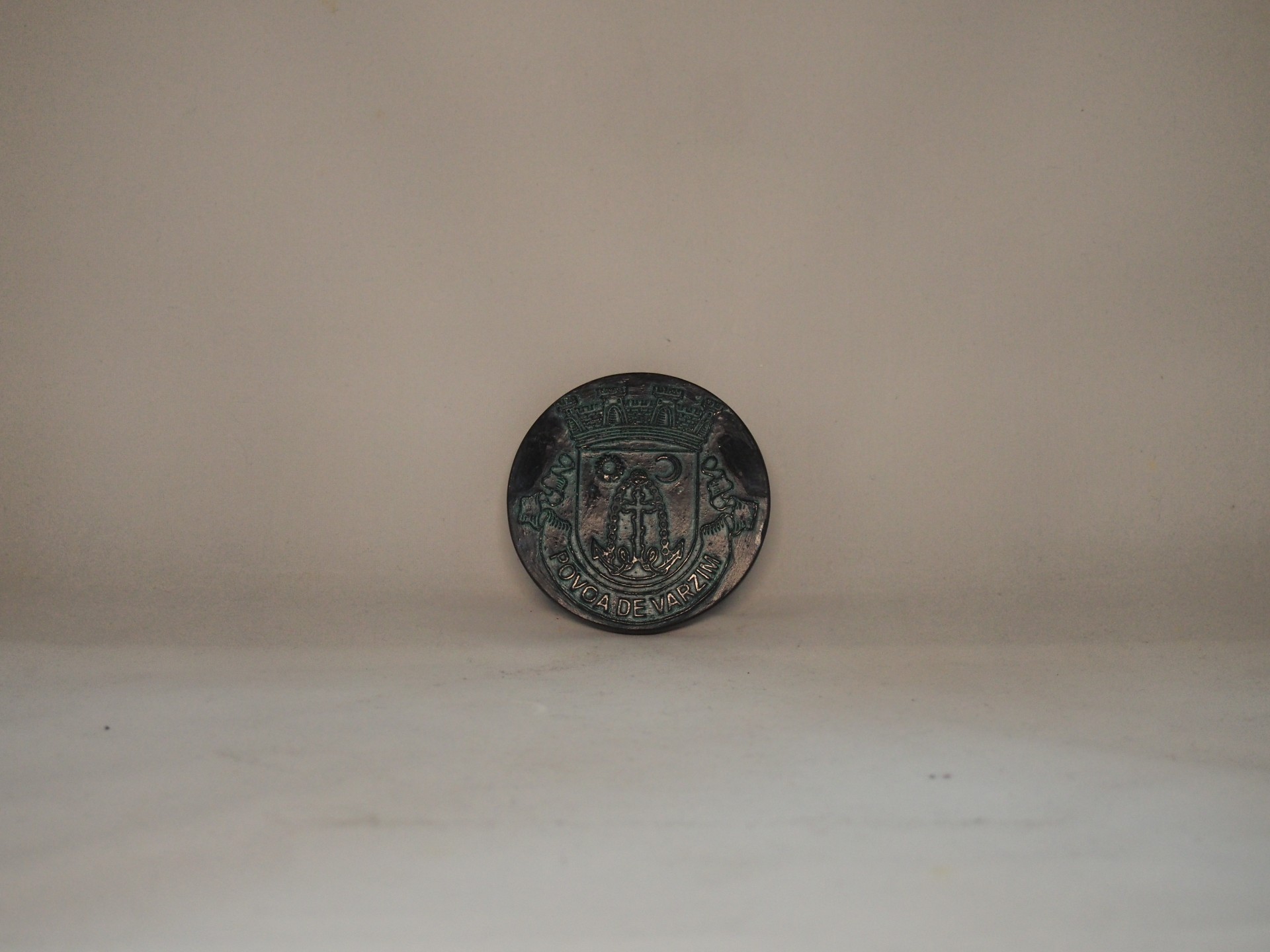 Botão metálico verde e preto com brasão e texto 'CAIXA ECONOMICA'