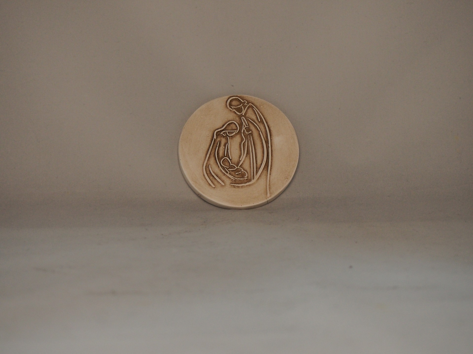 Medalha redonda de metal com relevo de figura feminina e criança