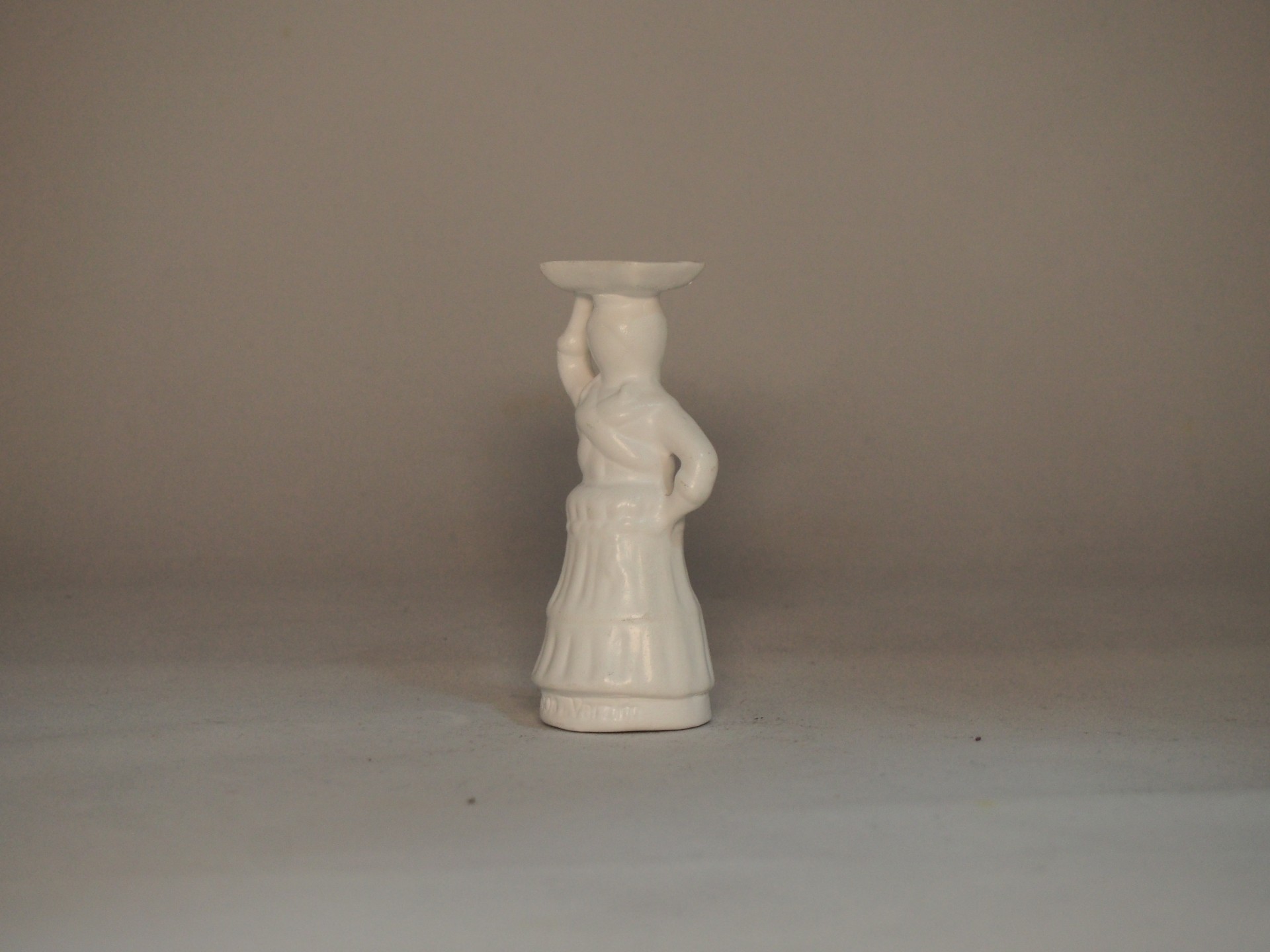Figura decorativa em cerâmica branca de mulher com prato na cabeça