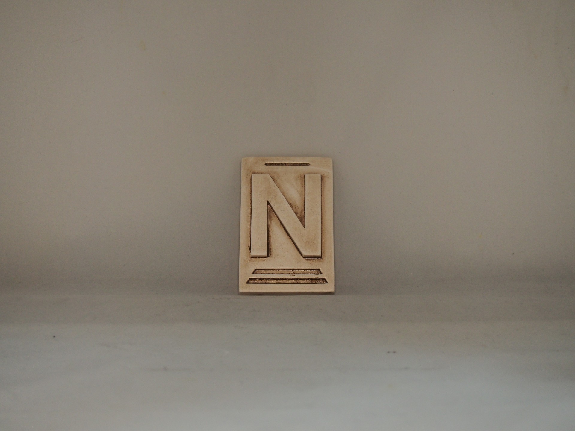 Bloco pequeno bege com letra N em relevo