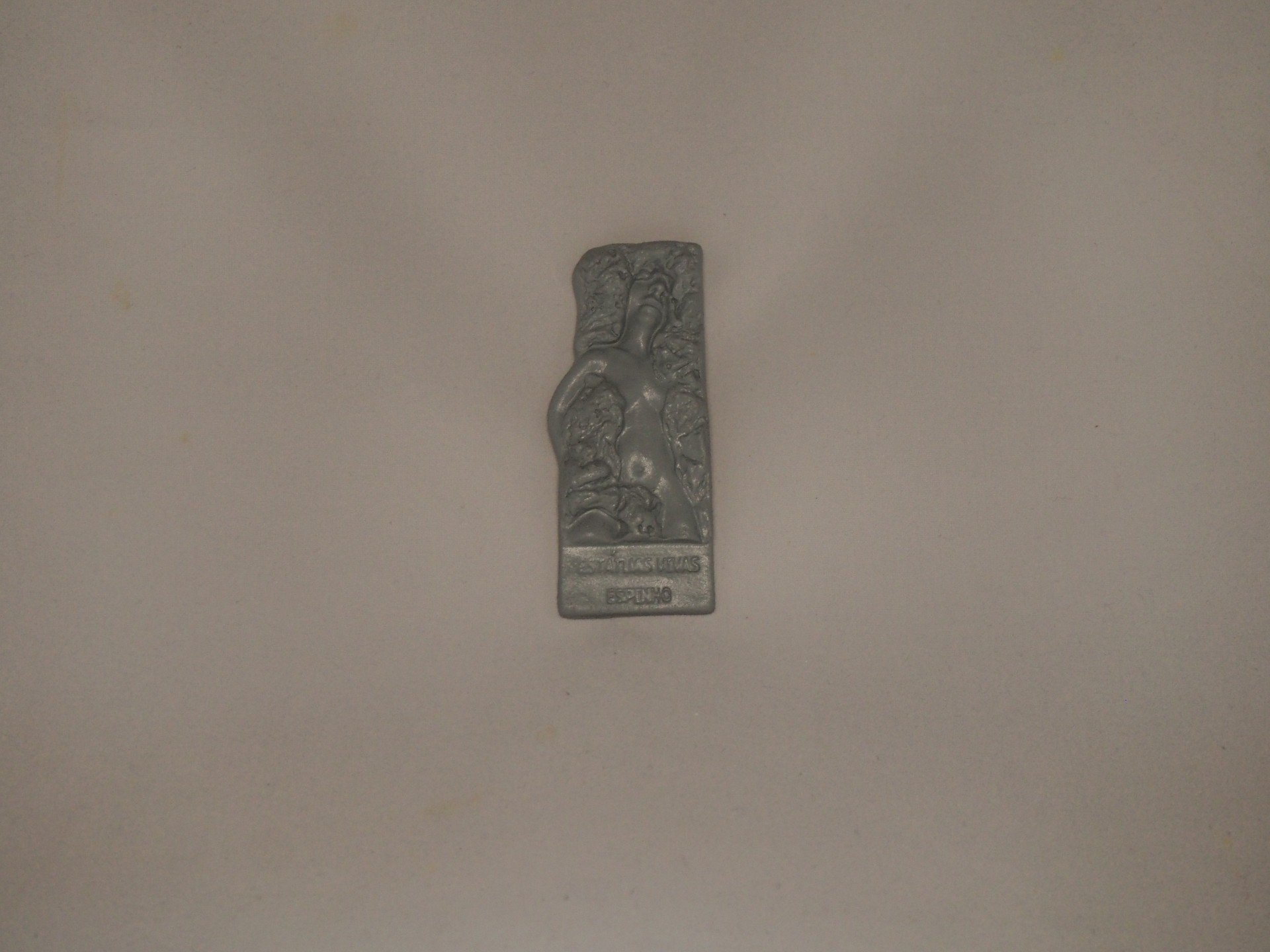 Objeto metálico decorado em relevo com texto SOLID BRONZE