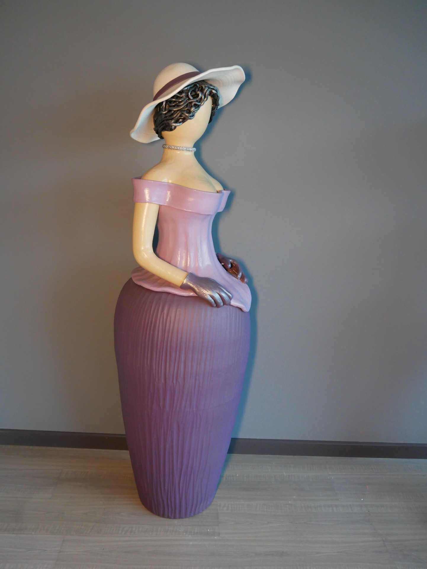 Figura decorativa feminina com vestido rosa e chapéu branco