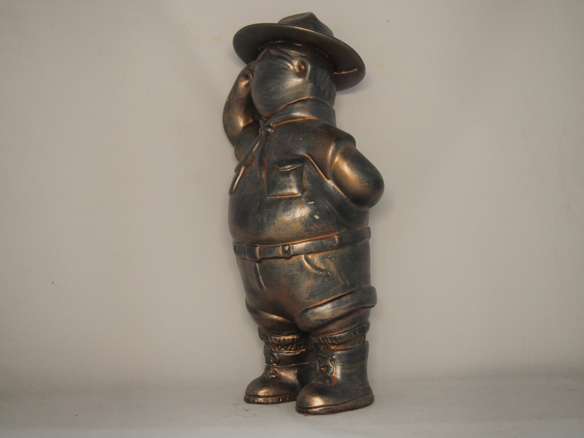 Estátua metálica em tom bronze de um urso a fazer continência