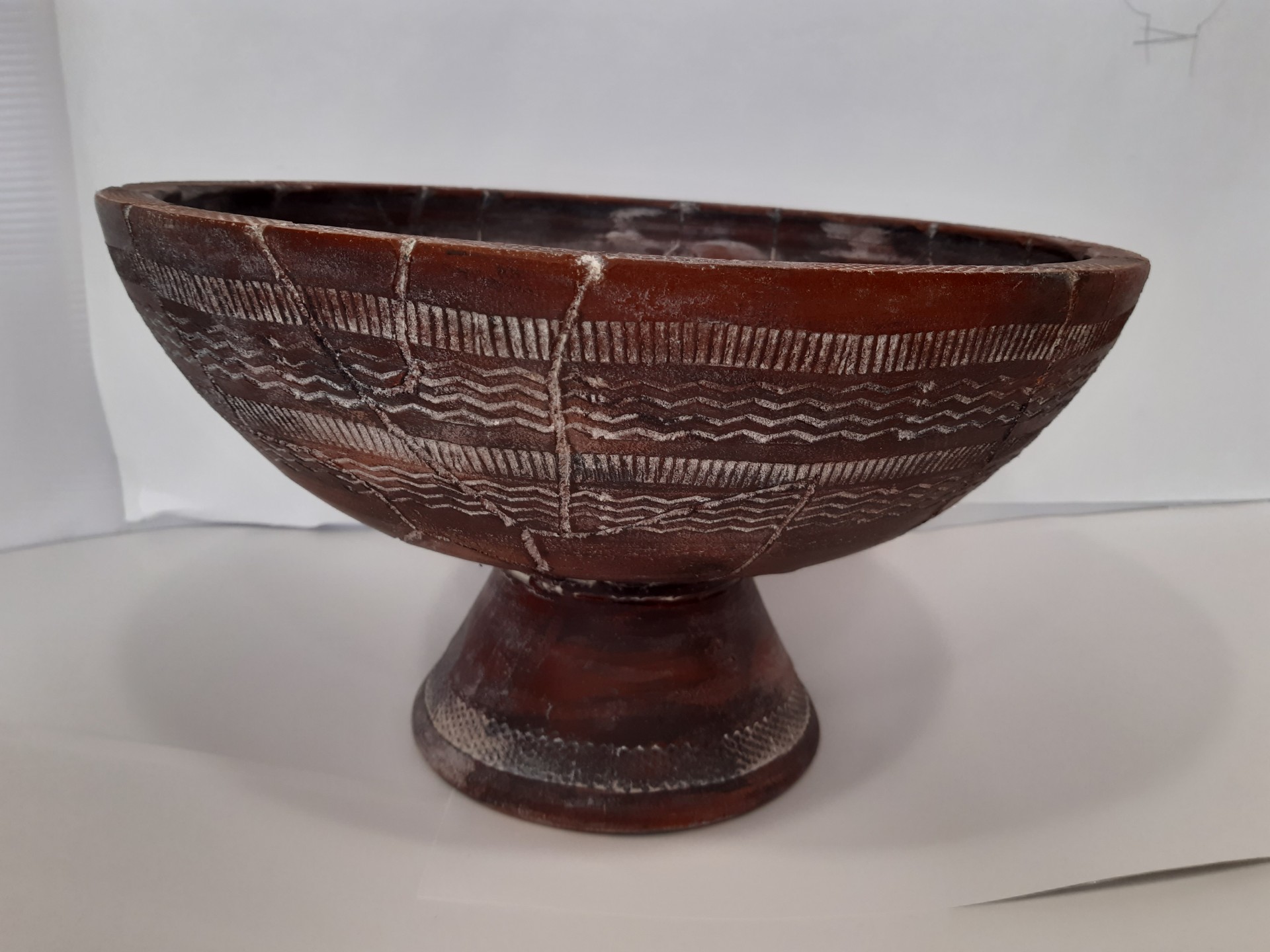 Tigela cerâmica marrom com padrões brancos e base arredondada