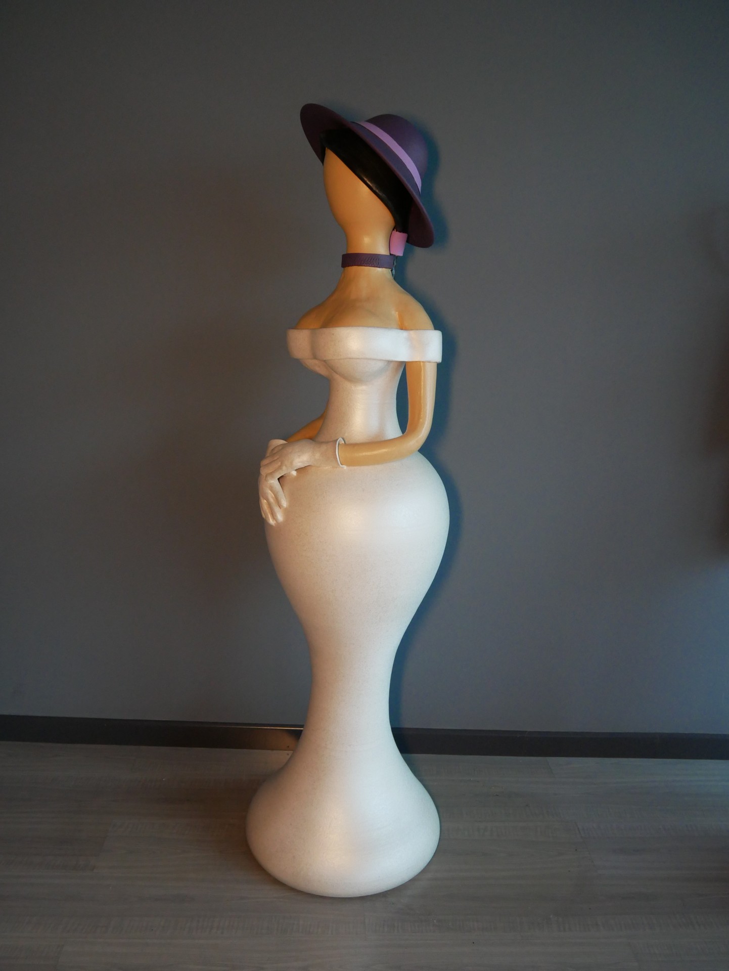 Estátua decorativa de mulher estilizada com chapéu roxo e vestido branco