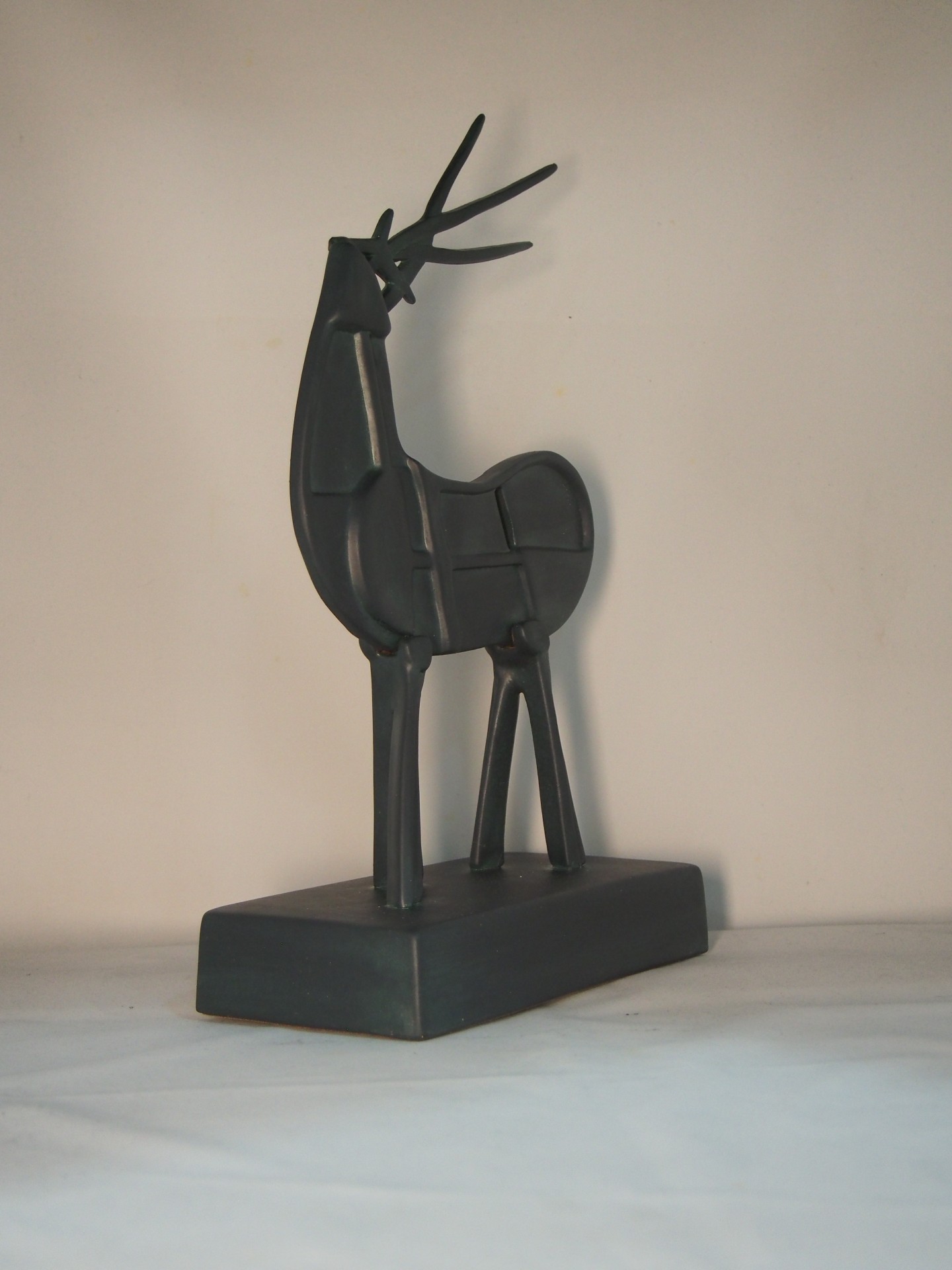 Escultura de veado preto em metal com base retangular