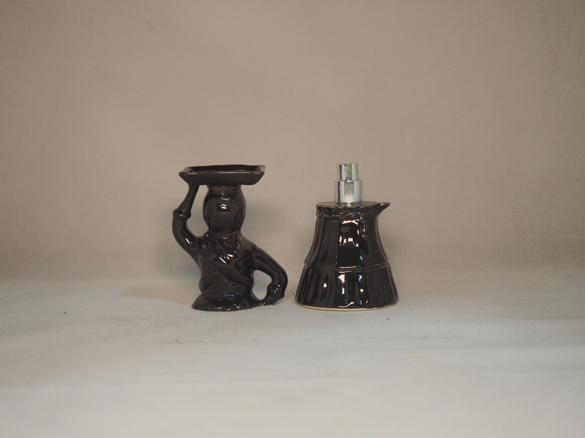 Frasco de perfume preto com tampa em forma de figura humana.