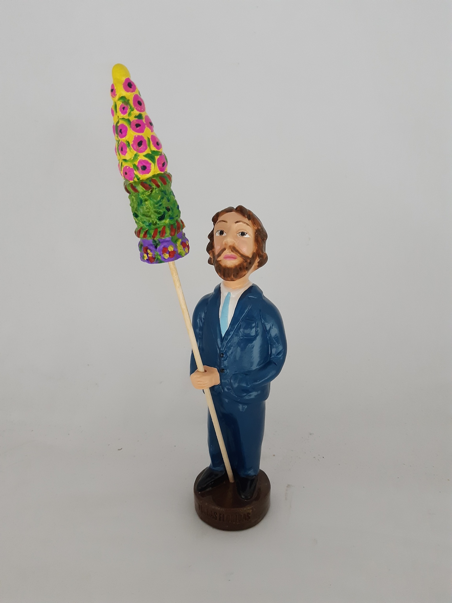 Estátua de homem com fato azul segurando vara com objeto colorido num fundo branco