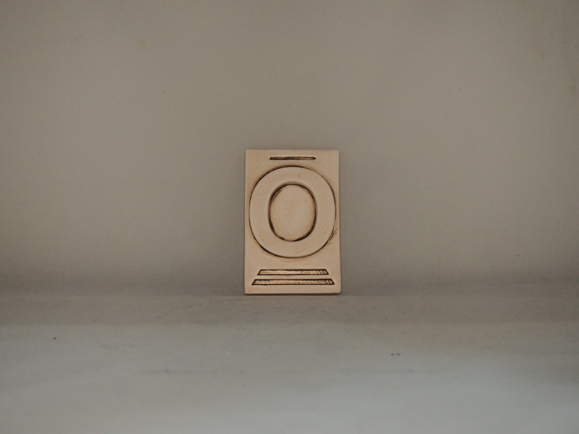 Objeto de cerâmica branco com relevo circular e linhas horizontais