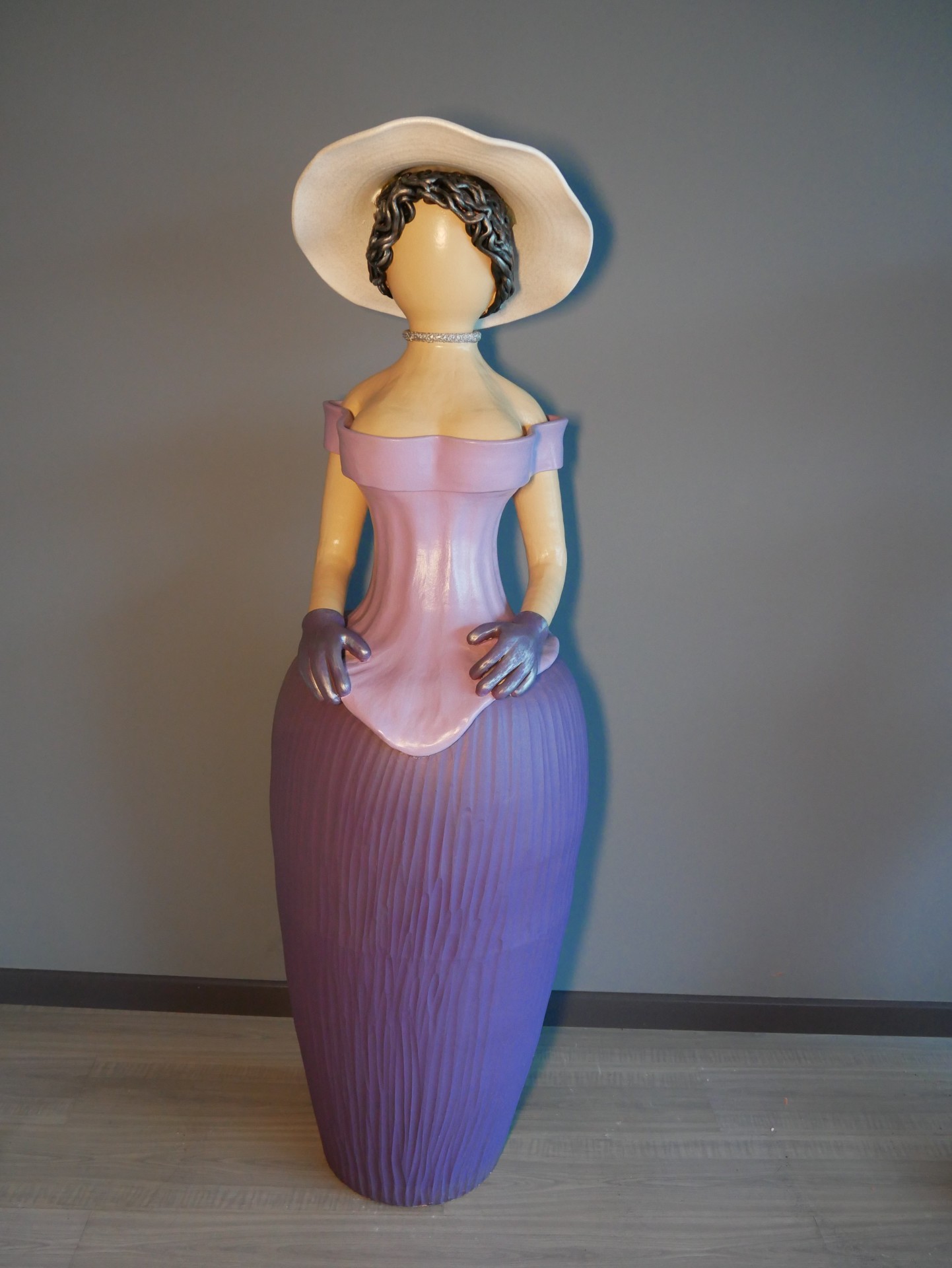 Estatueta de mulher com vestido longo e chapéu branco