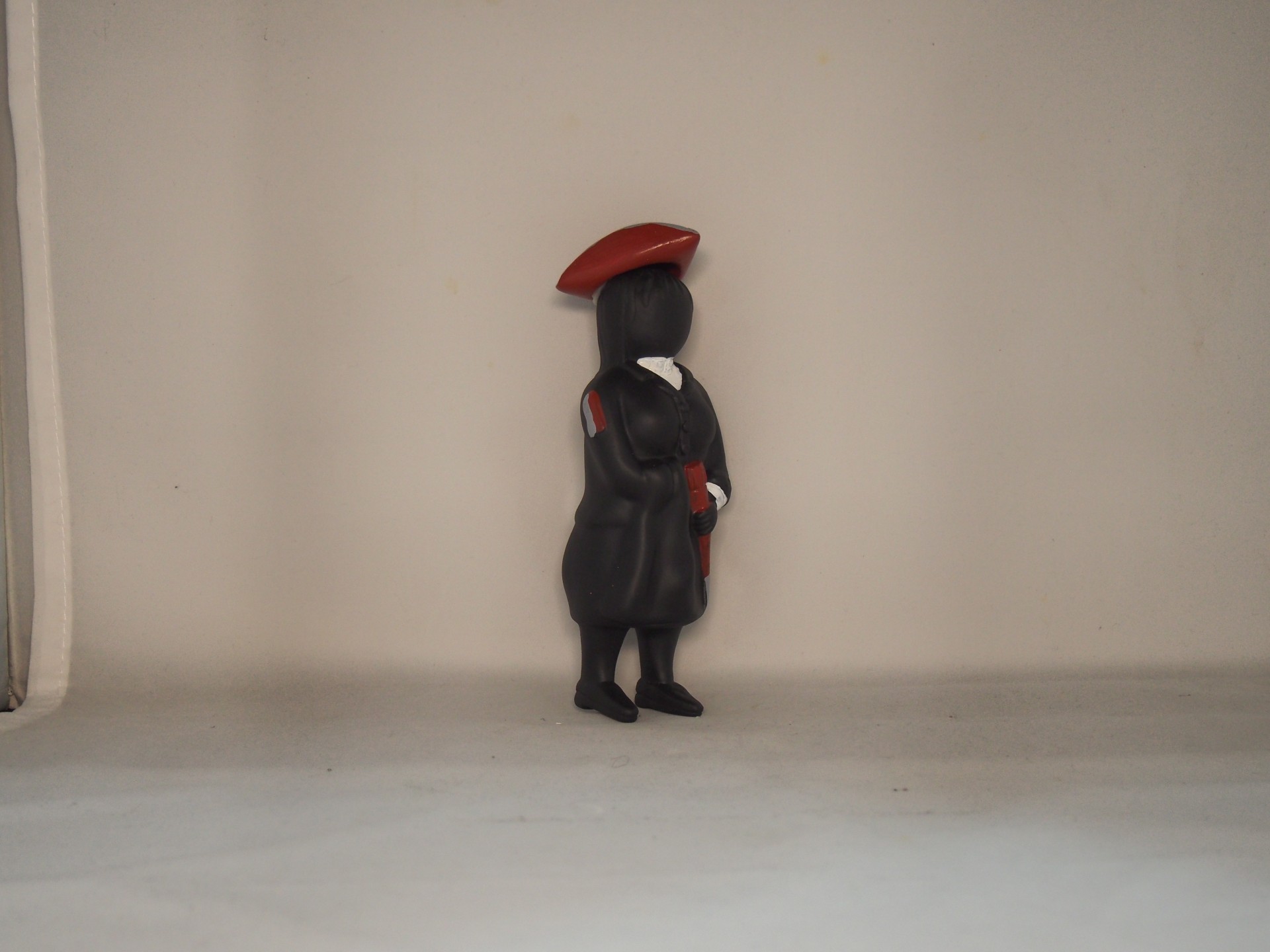 Figura decorativa de cerâmica com fato tradicional preto e boina vermelha