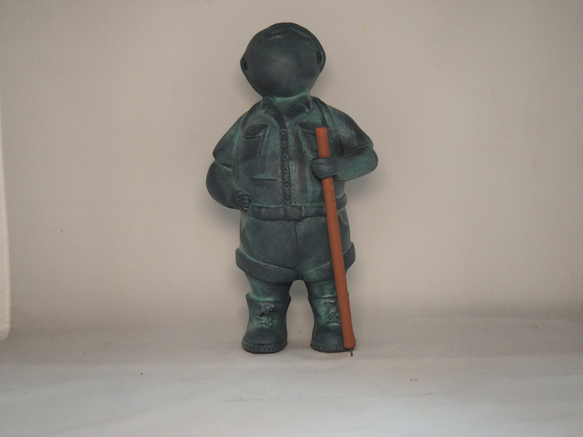 Estátua de pessoa com roupa escura e bastão castanho