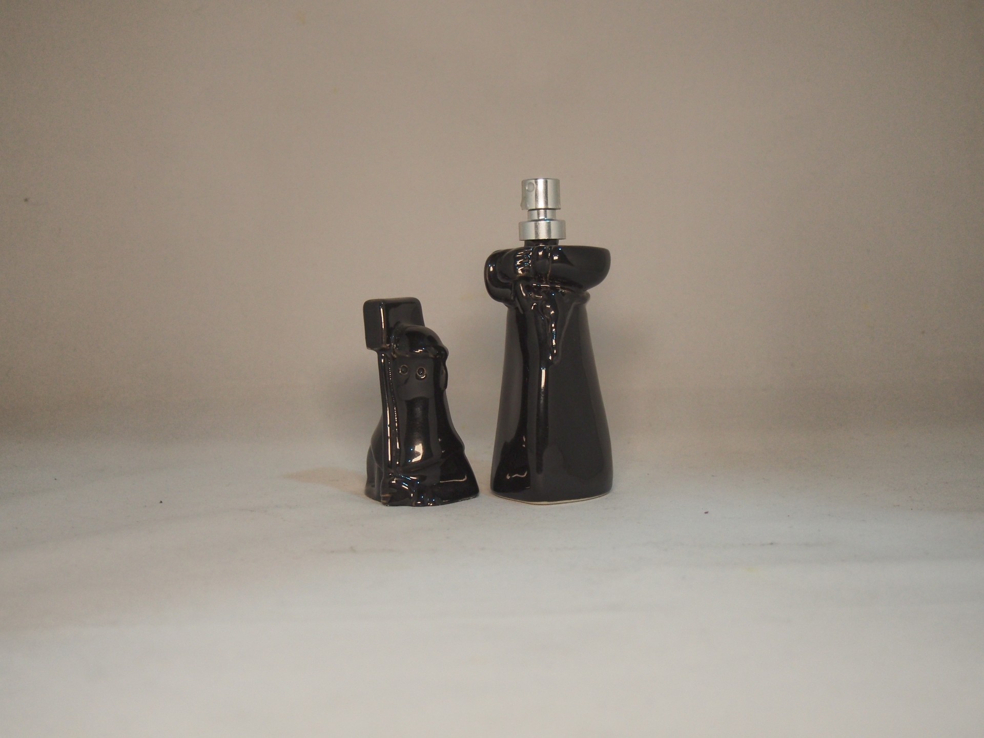 Dois frascos de vidro preto com formas arredondadas e tampa prata