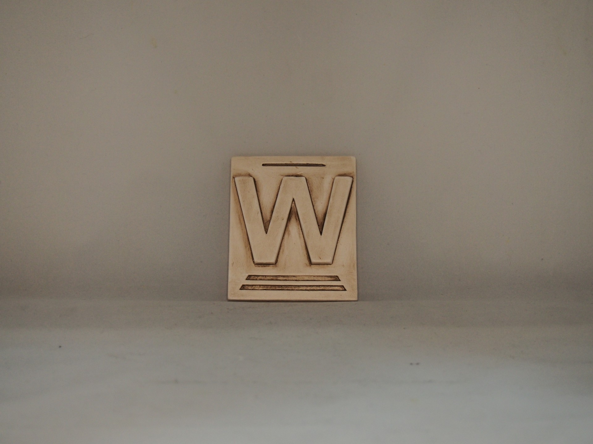 Bloco de madeira com a letra W gravada em relevo
