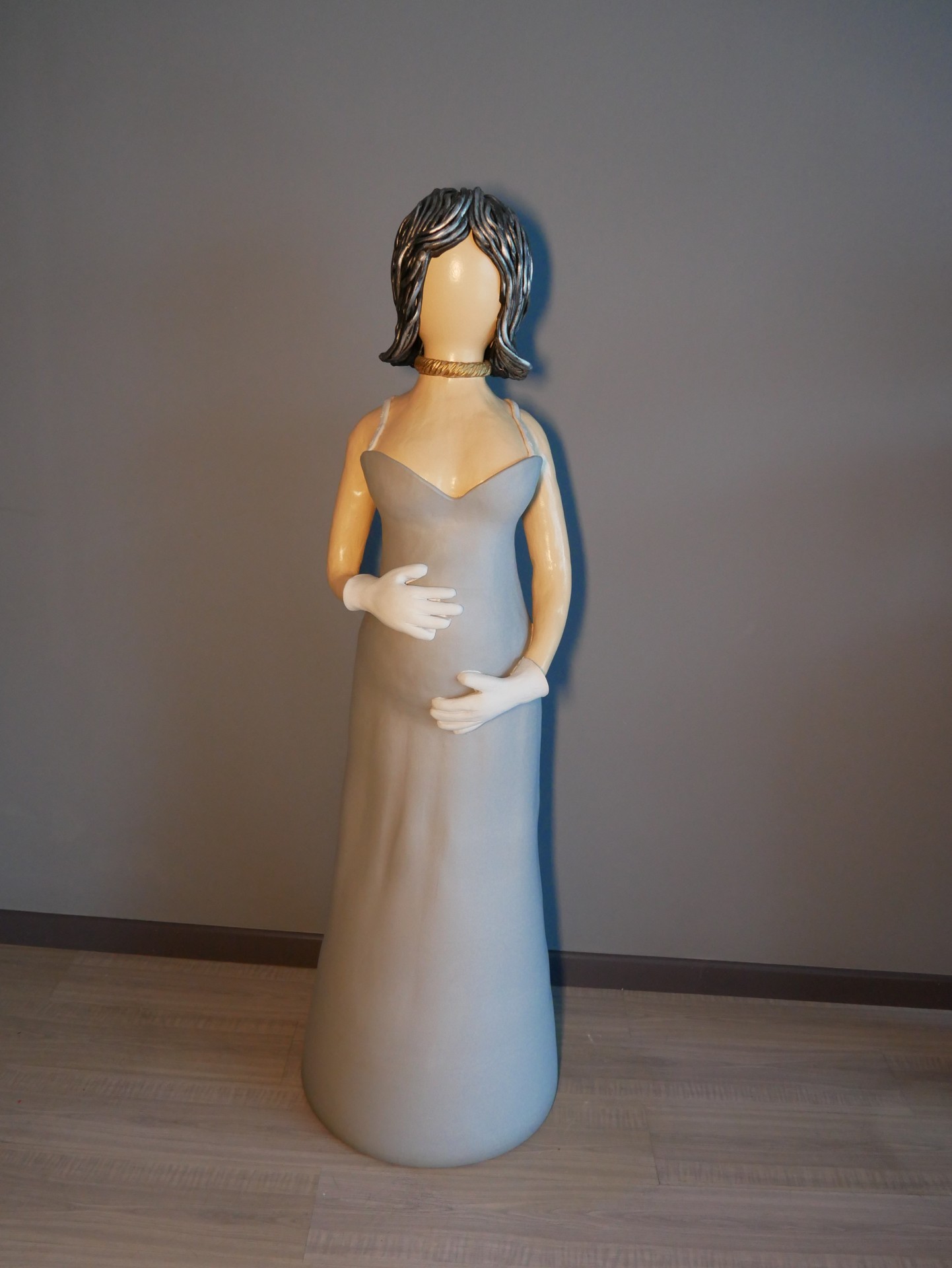 Estátua decorativa de mulher com vestido cinzento e luvas brancas