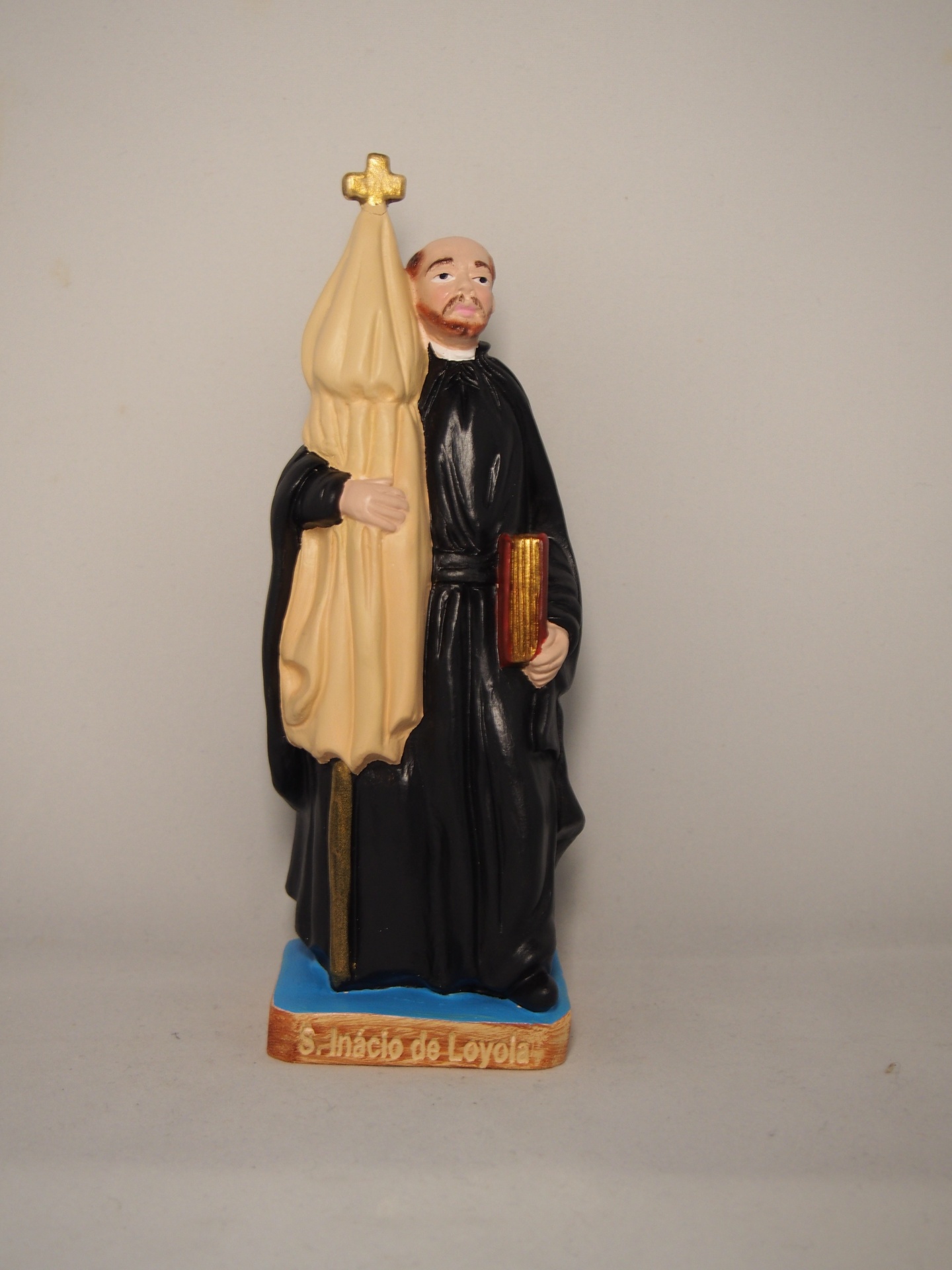 Estátua pintada de São Inácio de Loyola com bandeira e livro