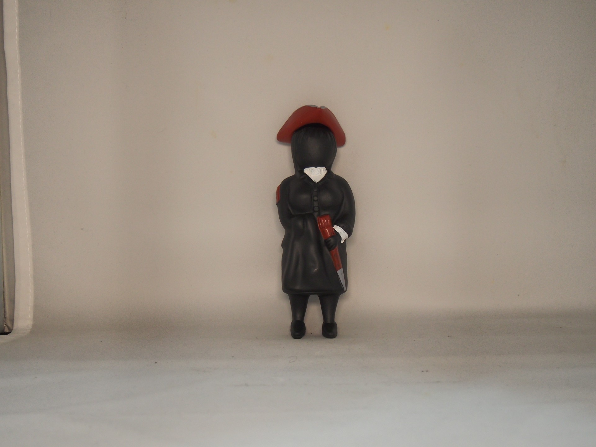 Figura decorativa preta com chapéu vermelho e faca