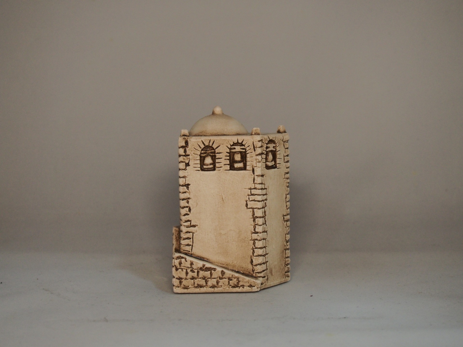 Miniatura de torre em cerâmica castanha clara com detalhes gravados castanhos.