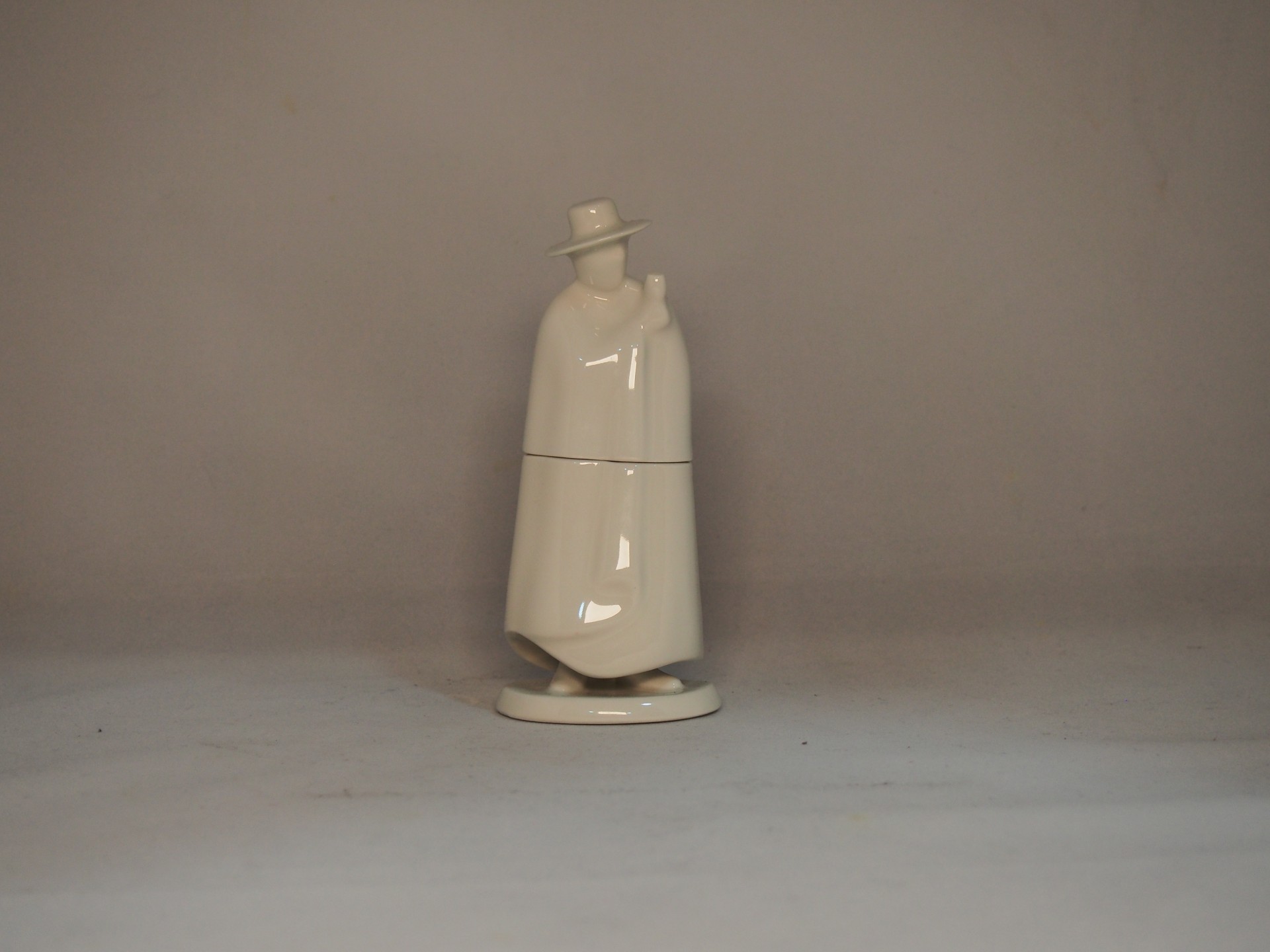 Figura decorativa branca em cerâmica com chapéu e sobretudo longo