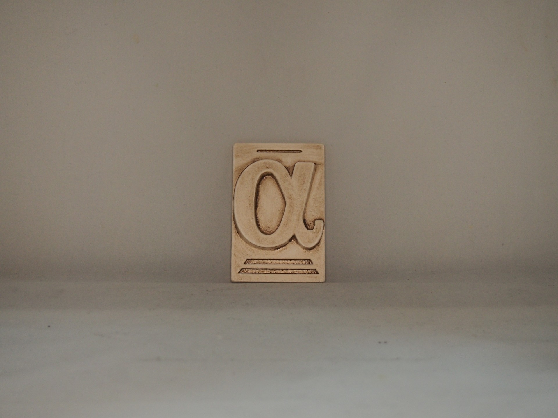 Bloco de madeira com símbolo alfa recortado