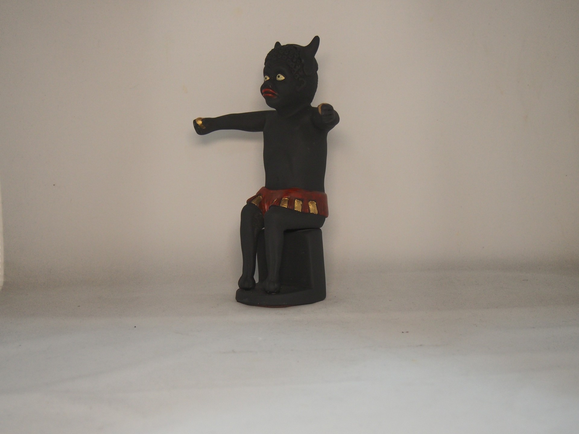 Estatueta negra sentada com detalhes vermelhos e dourados