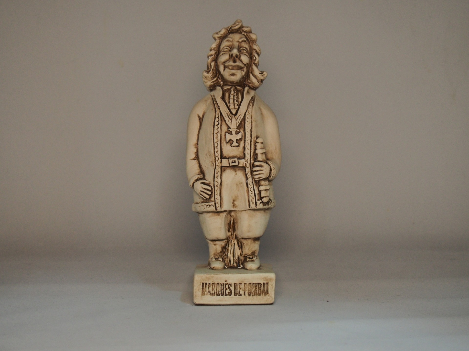 Estátua creme de figura humana com base e inscrição 'TAROUQUES DE UMBRIL'