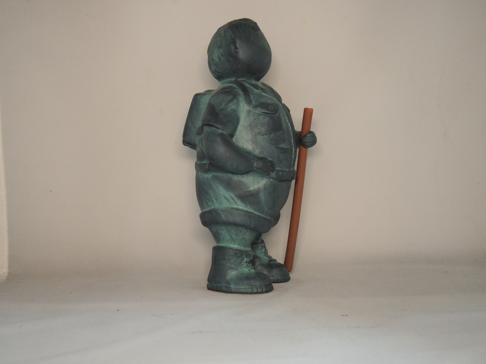 Estátua decorativa de um homem vestindo roupa verde escura segurando um cajado