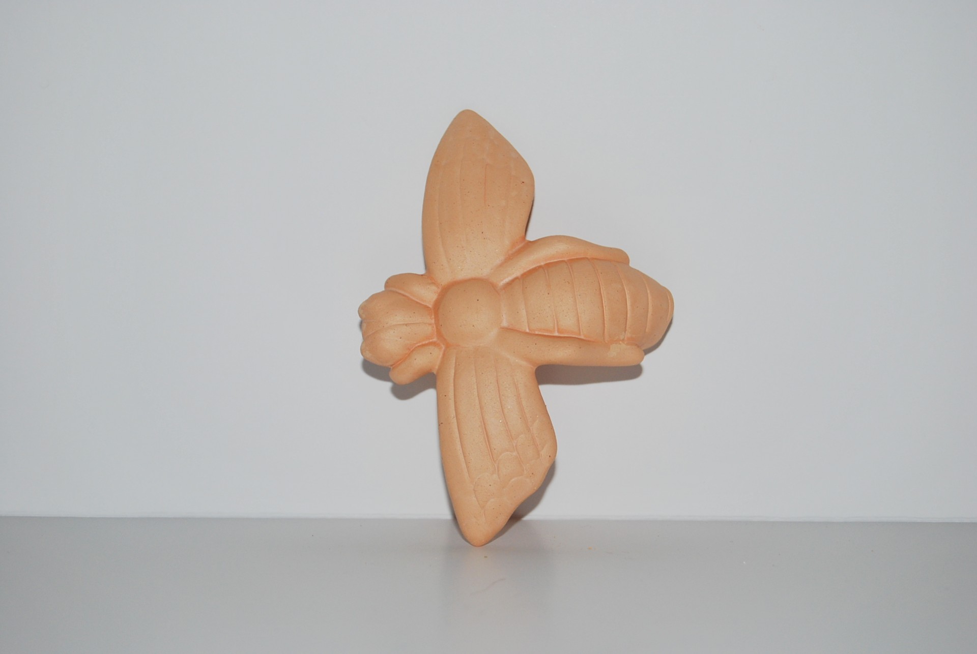 Escultura decorativa em forma de abelha em terracota sobre fundo branco