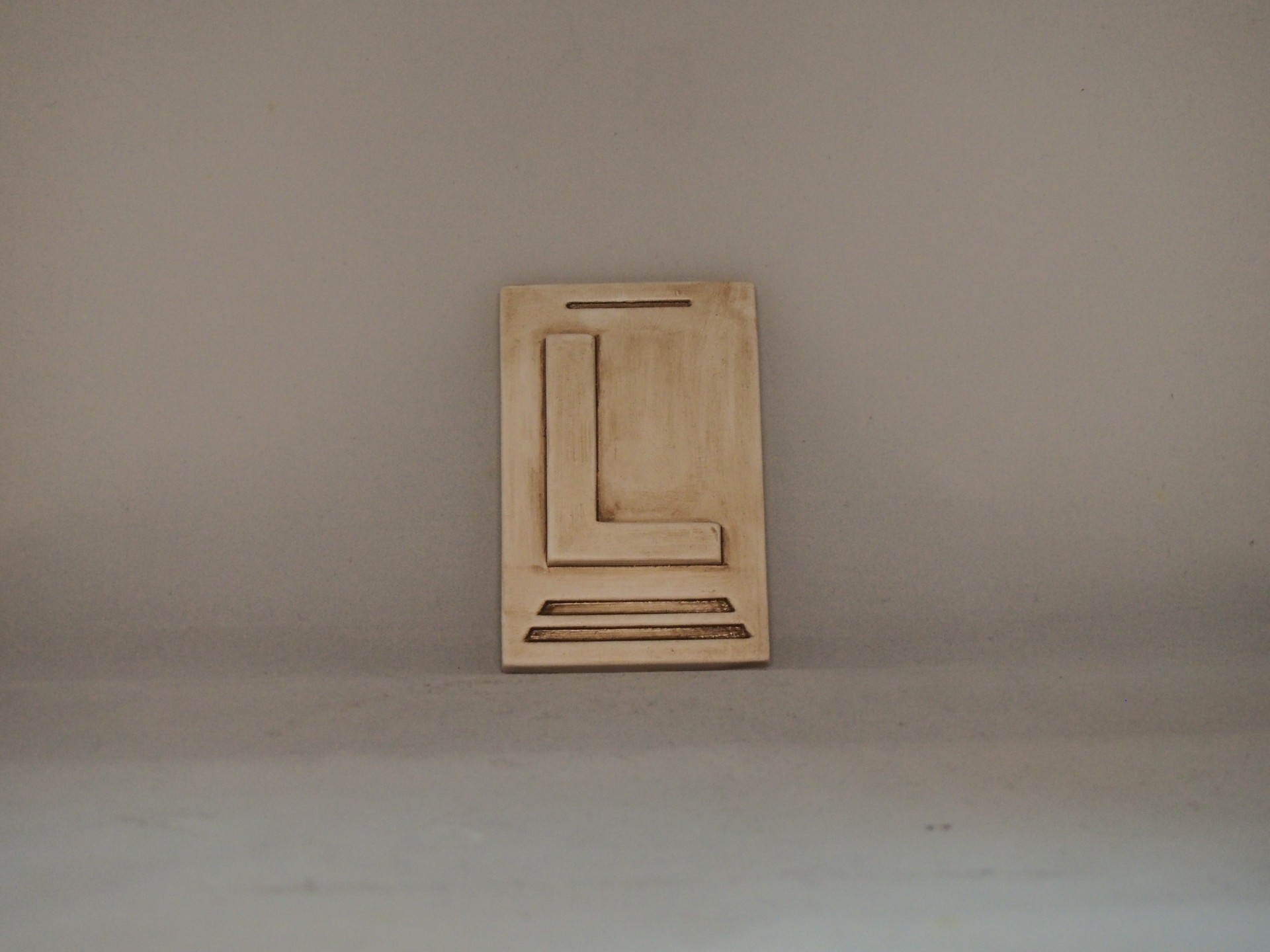 Placa decorativa de cerâmica bege com relevo geométrico em fundo cinza