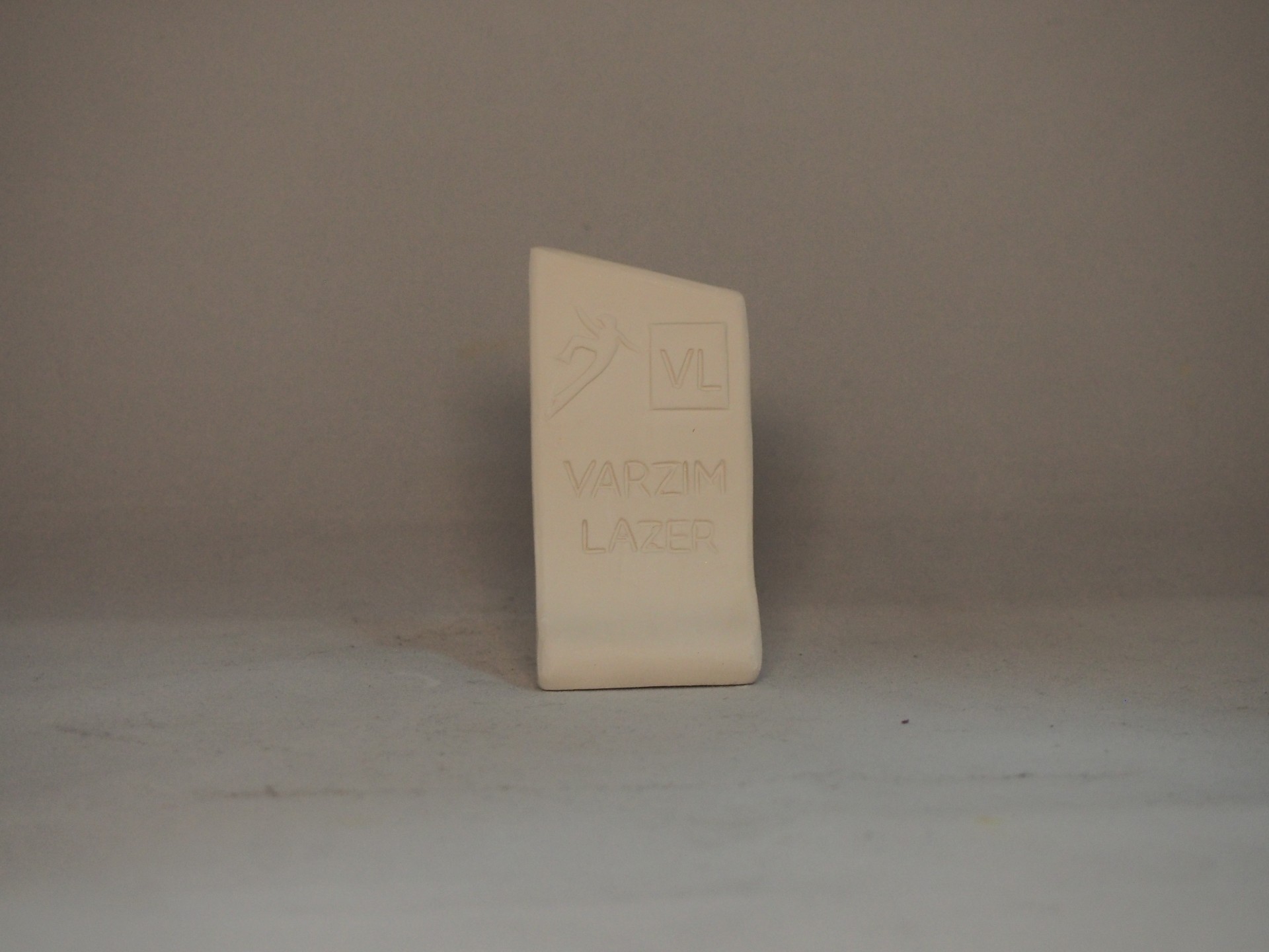 Produto cerâmico bege com inscrição VL VARZIM LAZER sobre superfície cinza