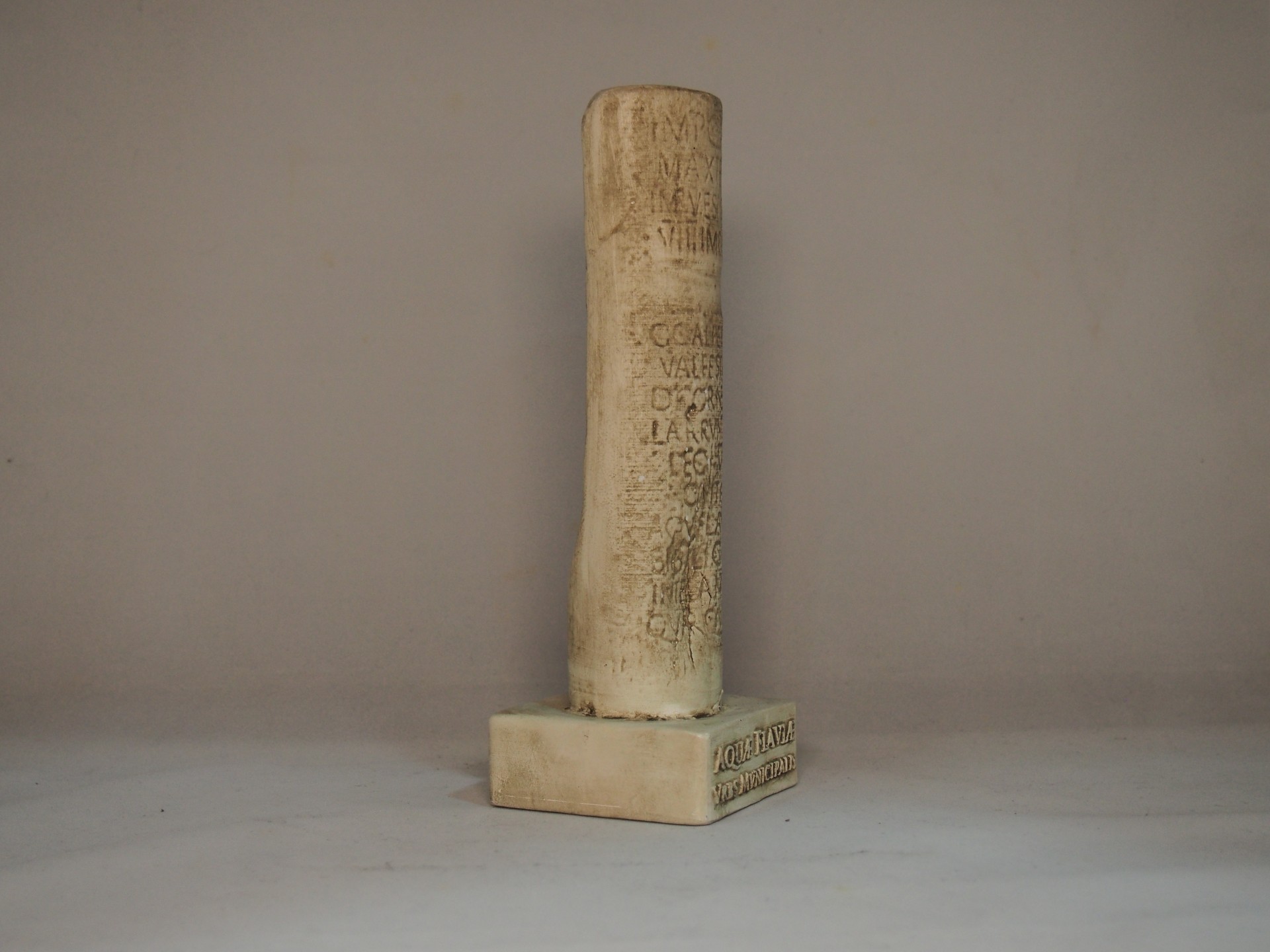 Coluna decorativa de pedra com inscrições gravadas sobre base quadrada