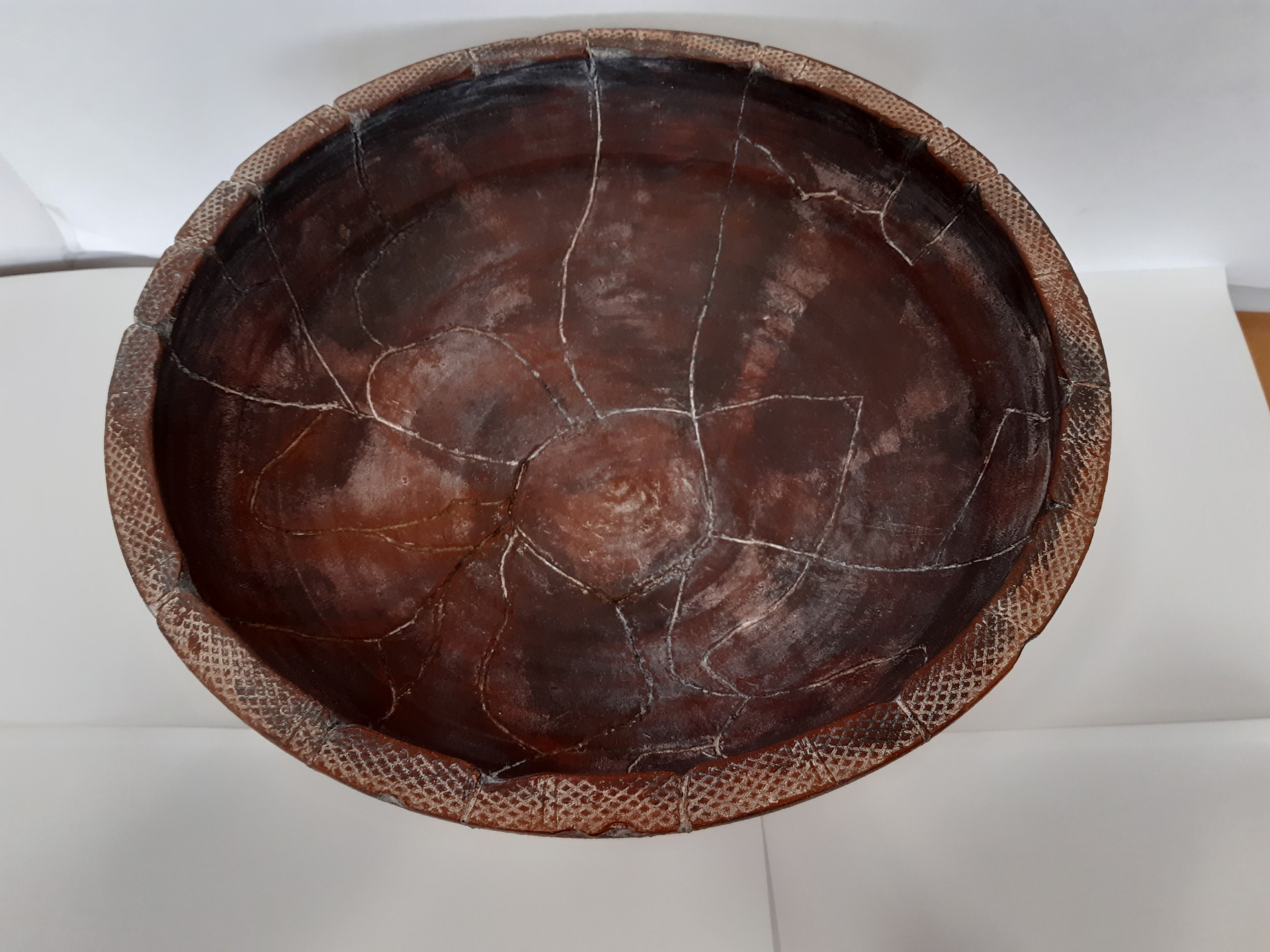 Taça de madeira grande com padrão geométrico na borda, rachas visíveis