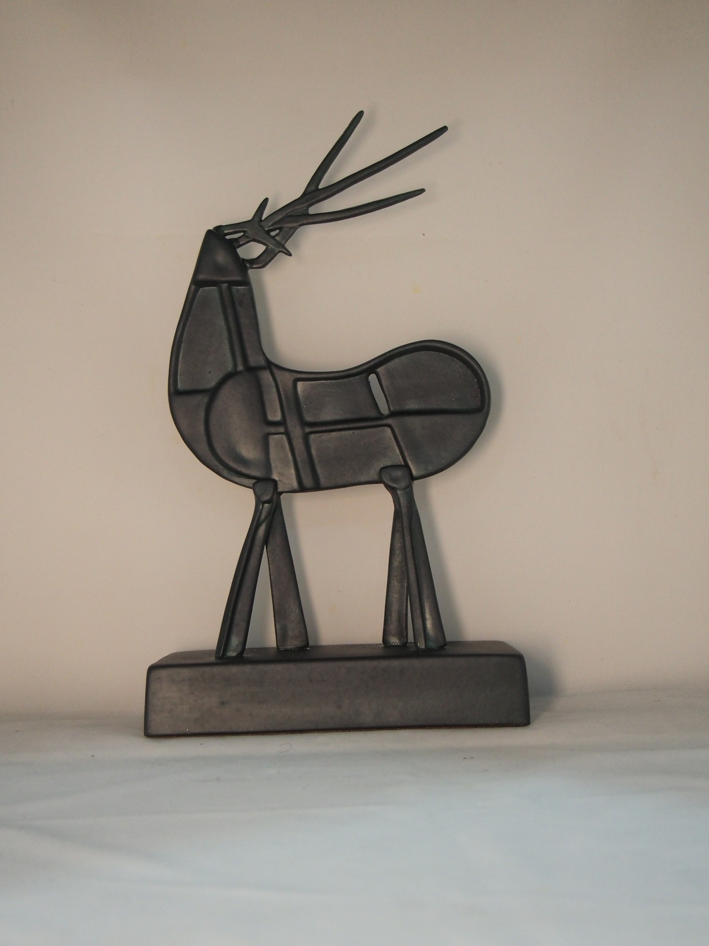 Escultura de metal preta em forma de veado estilizado