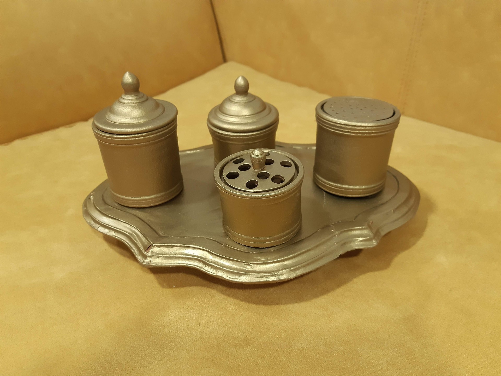 Conjunto dourado de frascos metálicos com tampa sobre bandeja dourada