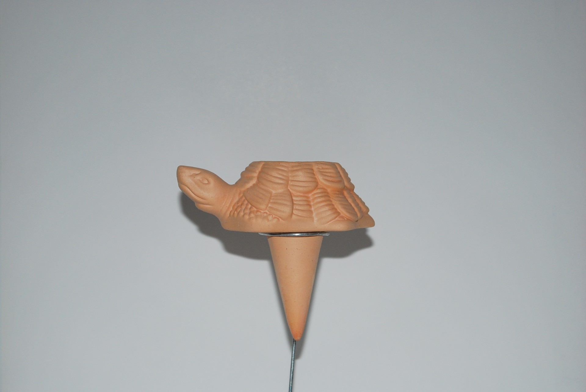 Objeto decorativo de terracota em forma de tartaruga sobre suporte metálico