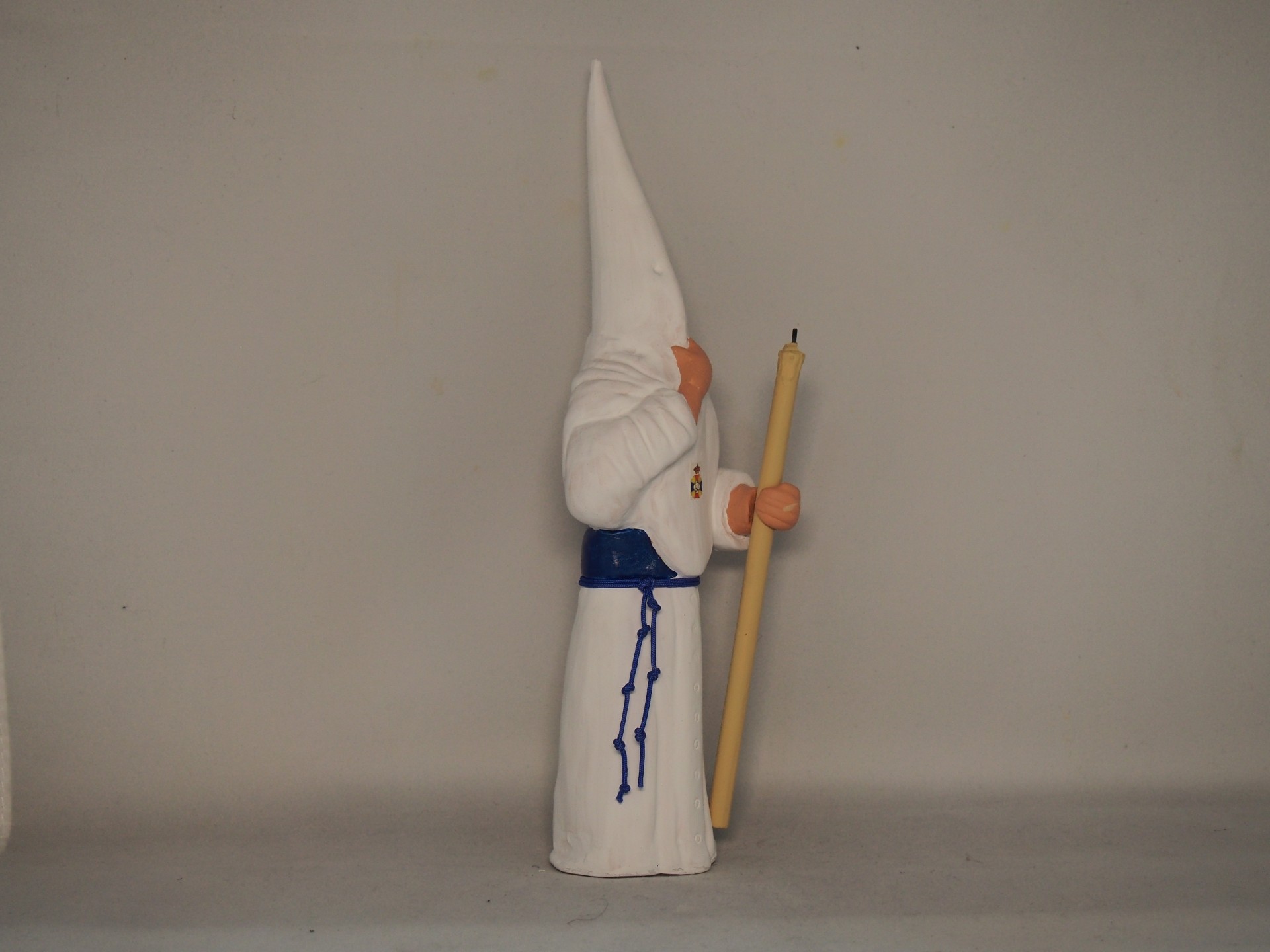 Estatueta de figura com túnica branca e capuz com vela amarela