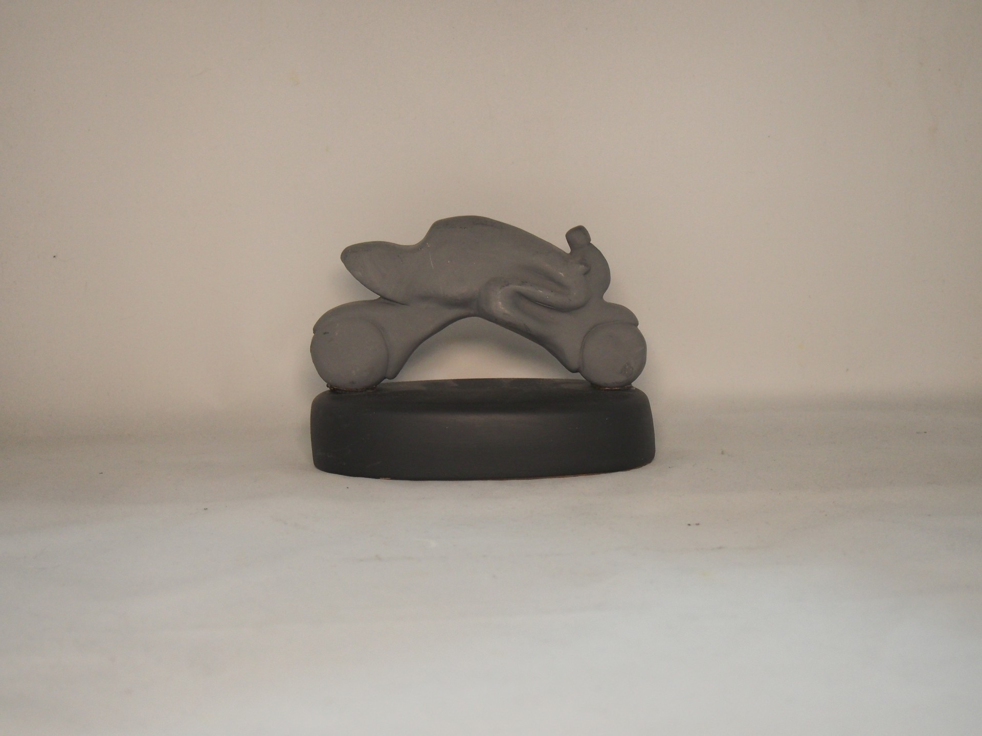 Objeto decorativo em forma de motocicleta cinzenta sobre base preta