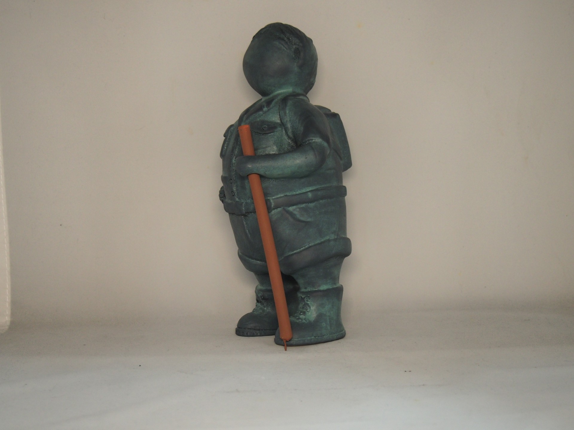 Estátua decorativa de menino segurando lápis grosso de metal verde-azulado