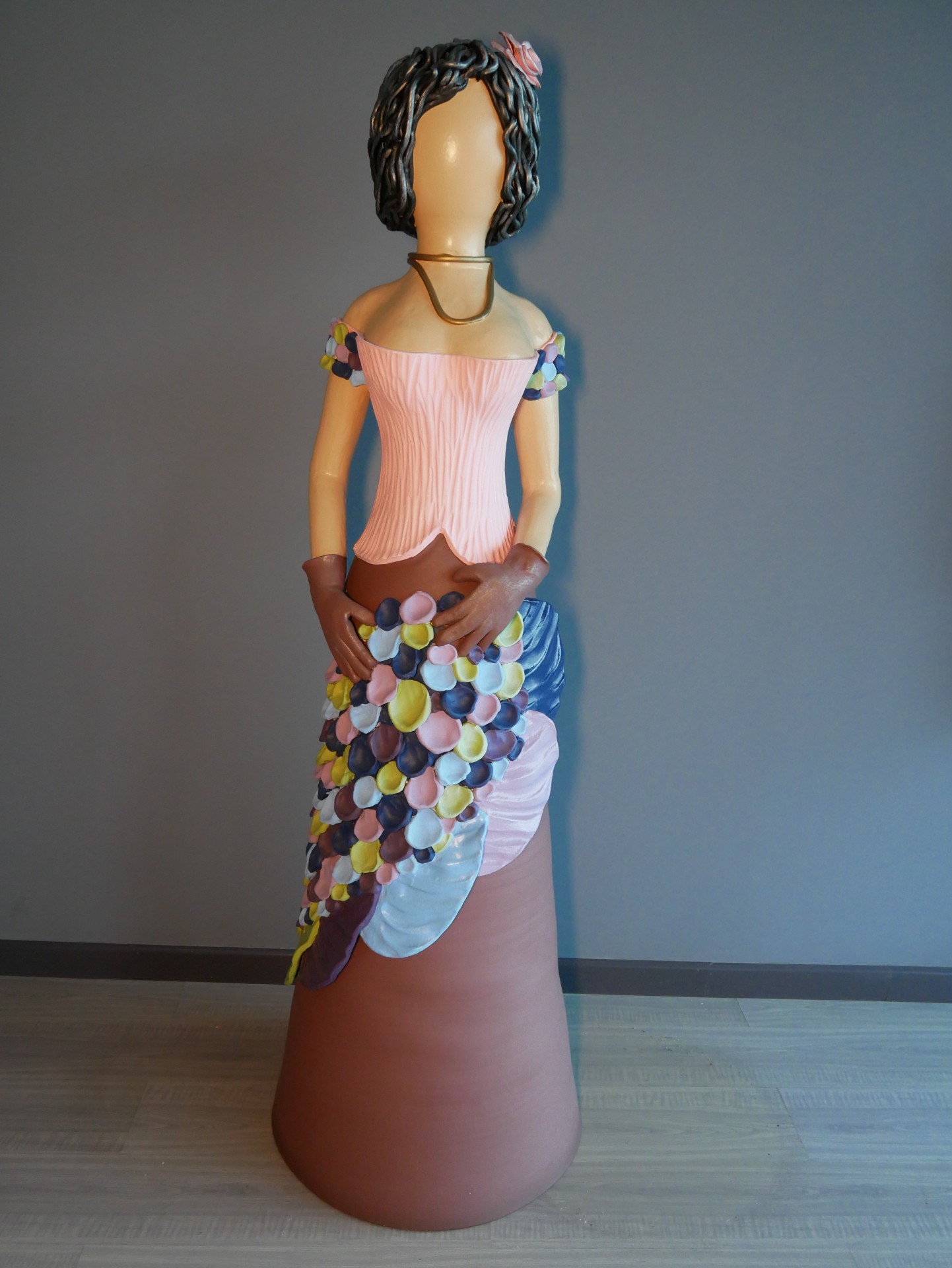 Estátua decorativa de mulher com vestido colorido e cabelo encaracolado