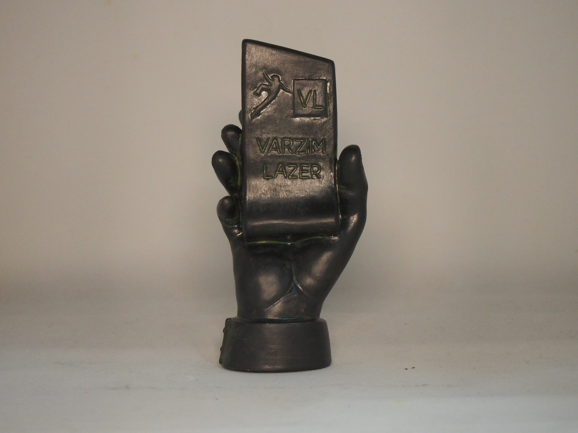 Escultura de mão preta segurando um cartão com texto em relevo