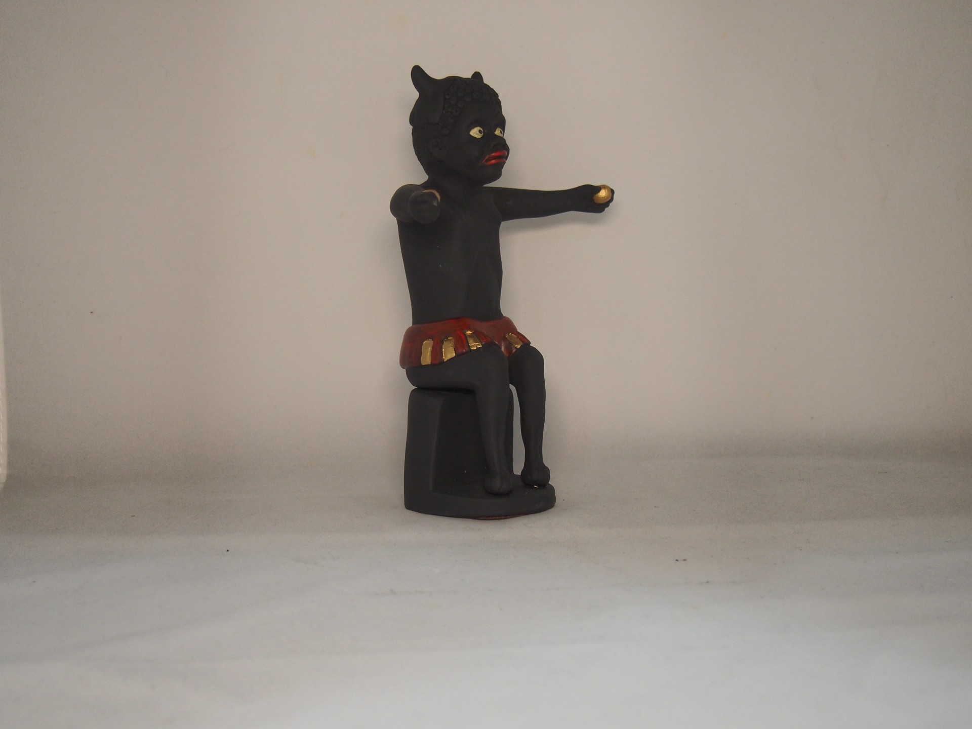 Figura artesanal de gato negro sentado com detalhes em vermelho e dourado
