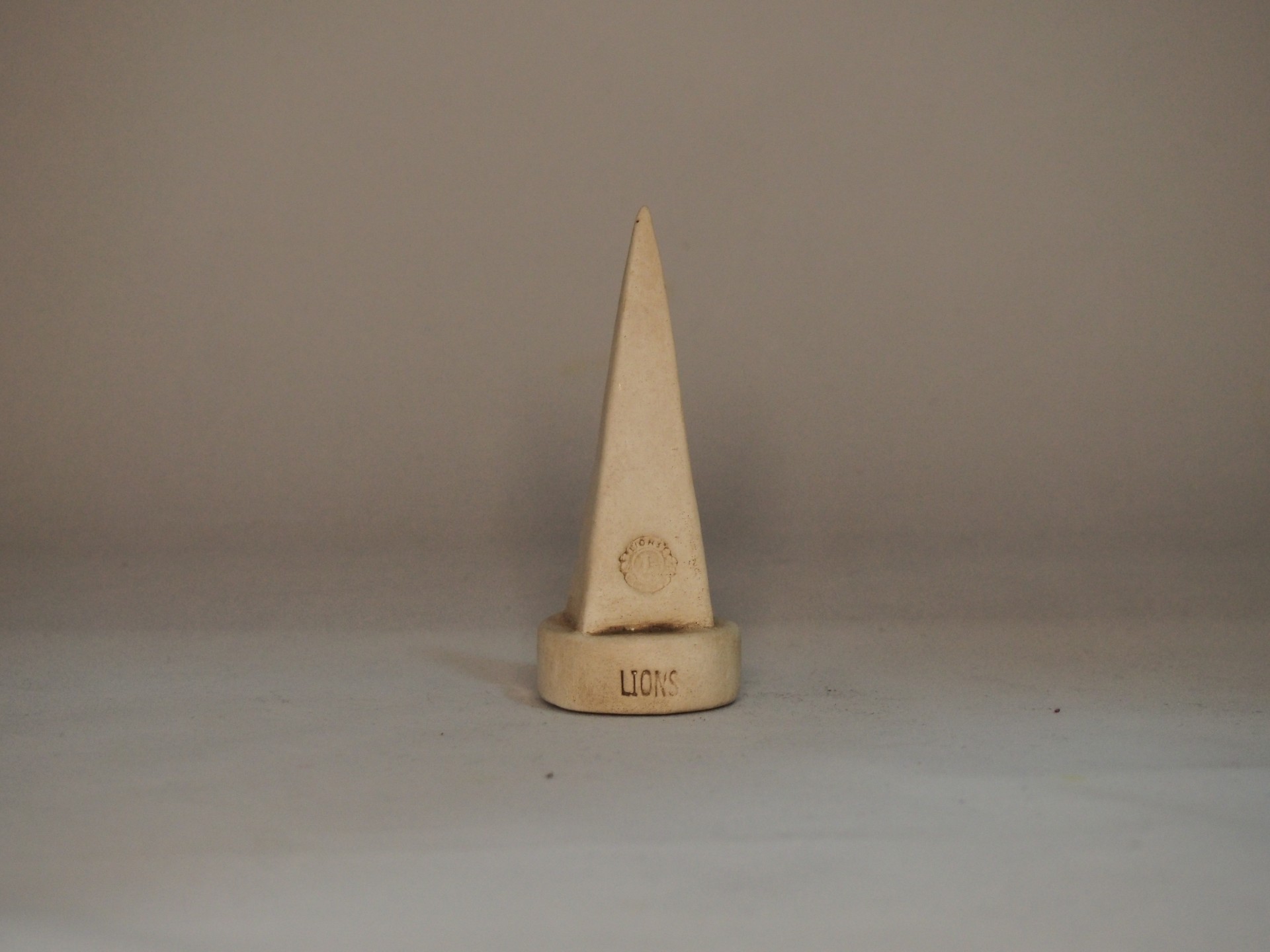 Suporte para anéis de madeira clara em forma de cone com base redonda e gravações.