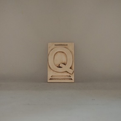 Placa de madeira com a letra Q em relevo